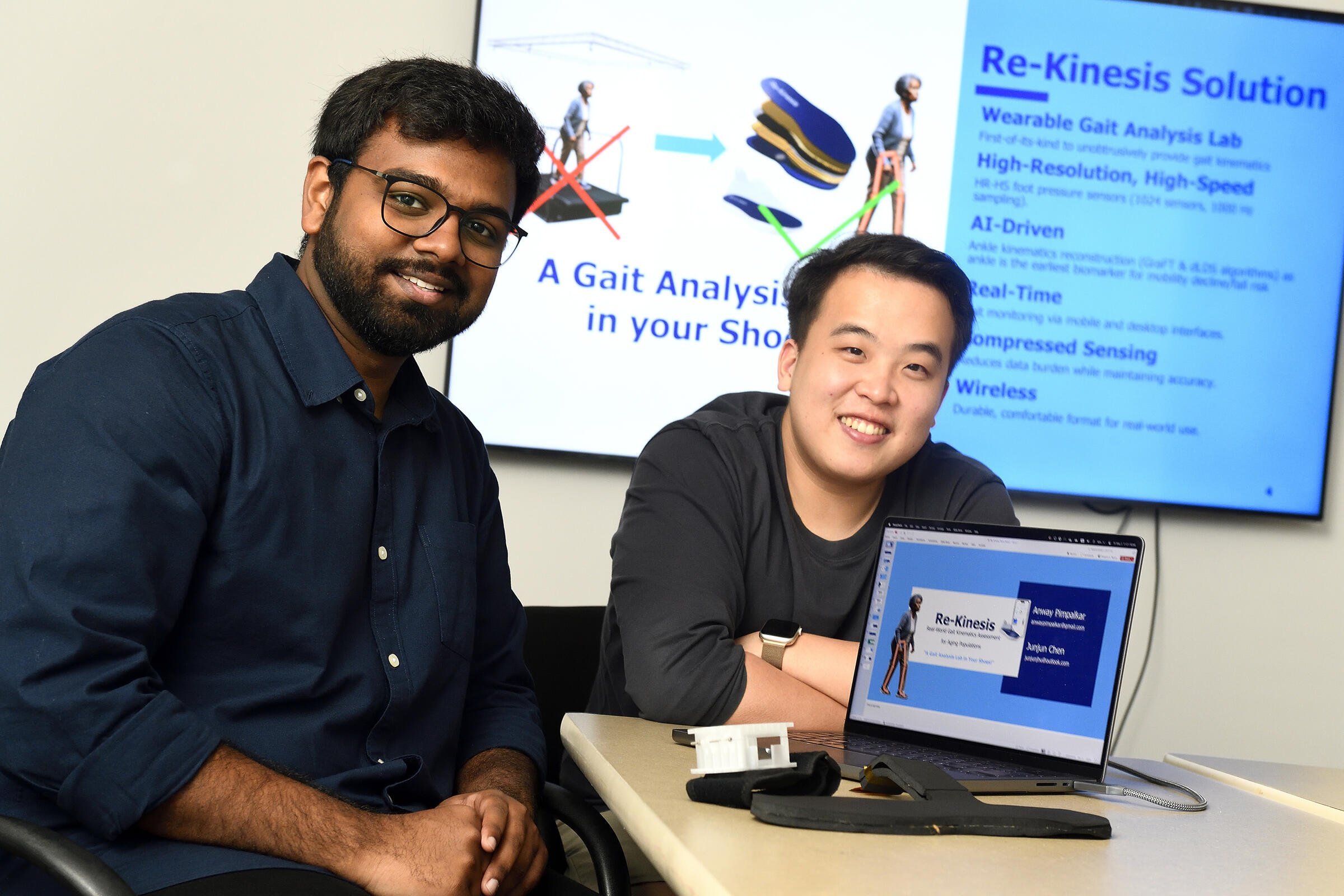 Two male students are sitting by a computer.