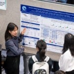 Student points at poster to explain it to others