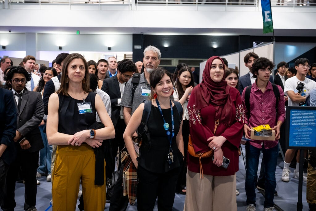 A crowd looks on while someone presents.