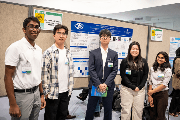Students pose in front of their poster.